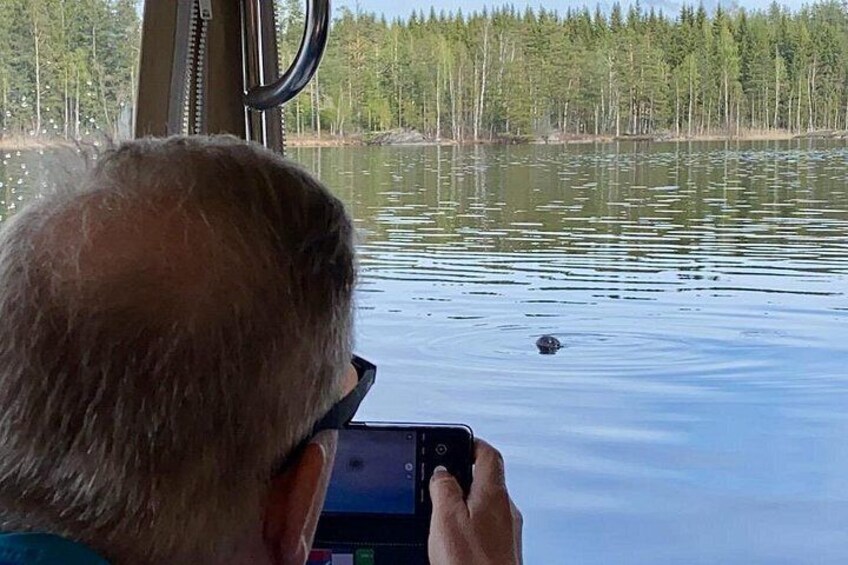 A person taking a photo of a water body with trees in the background. 2