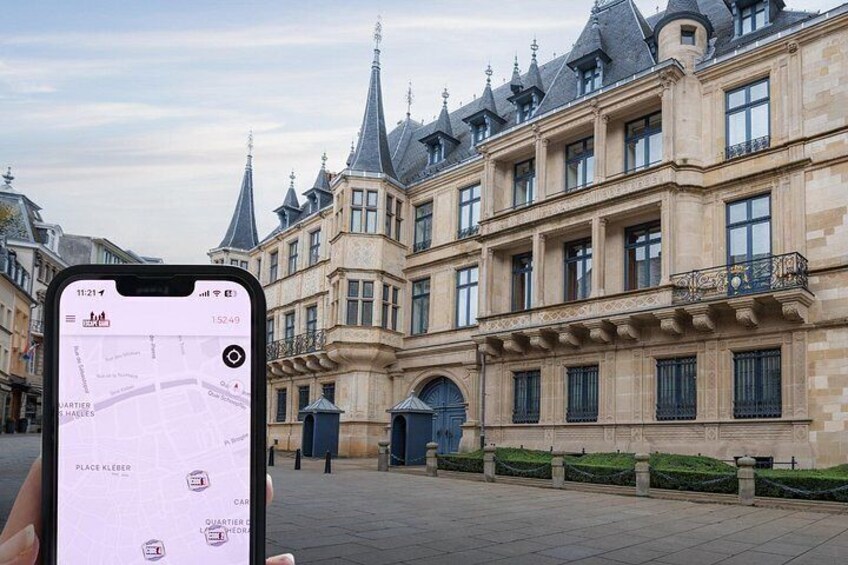 A historic building with ornate architecture, a paved courtyard, and a smartphone displaying a map. 4