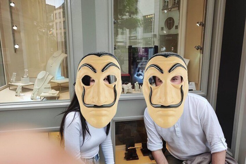 Two people wearing masks in front of a store window with jewelry on display. 5