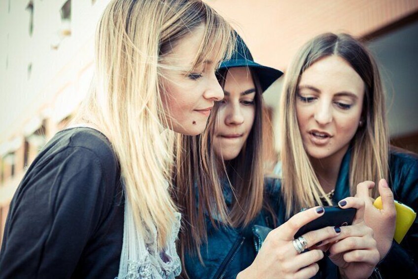 Three individuals looking at a smartphone. 3