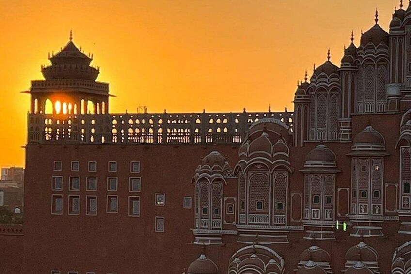 Un edificio grande y ornamentado con detalles arquitectónicos intrincados y una torre con balcón, sobre un cielo al atardecer. 3