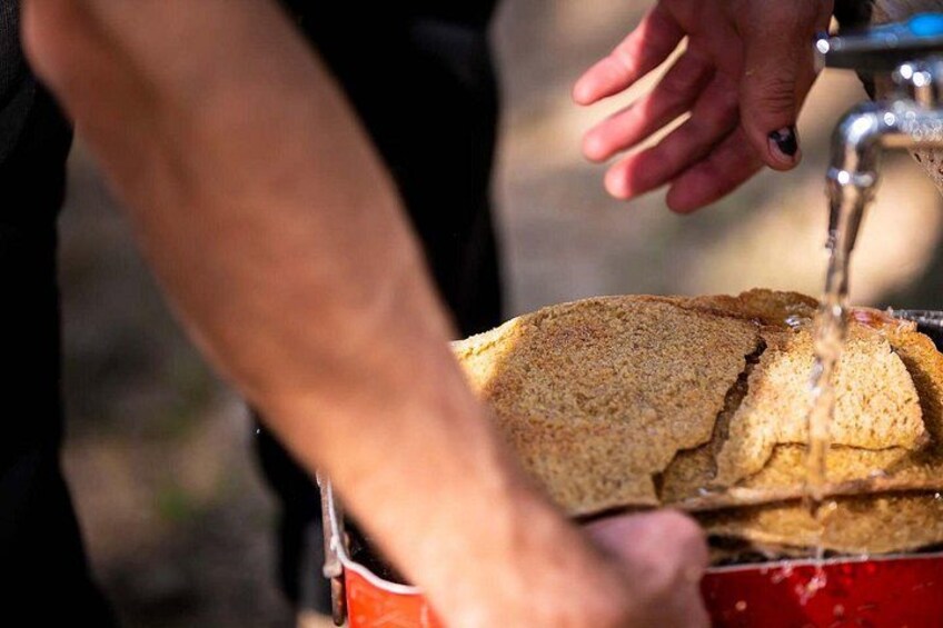 A person washing bread in a red bucket. 2