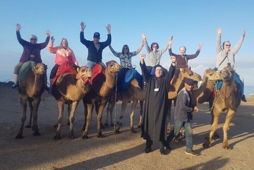 A group of people riding camels in a desert setting. 1