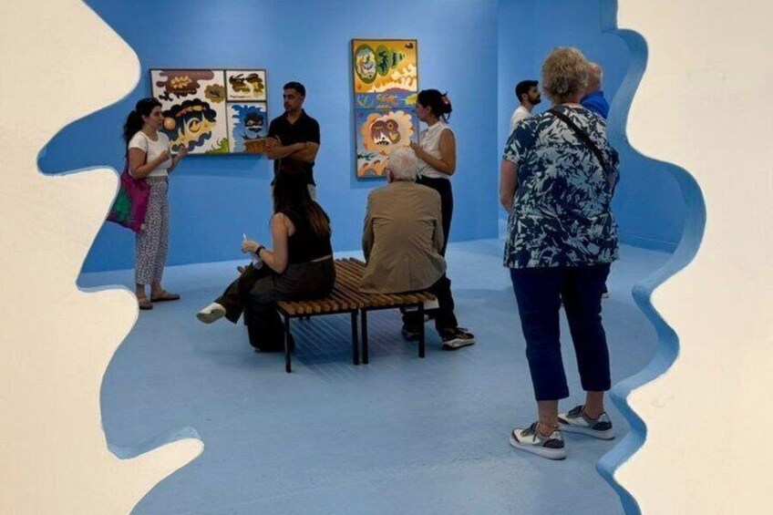 Mensen in een kunstgalerie met kleurrijke schilderijen aan de muur. 1