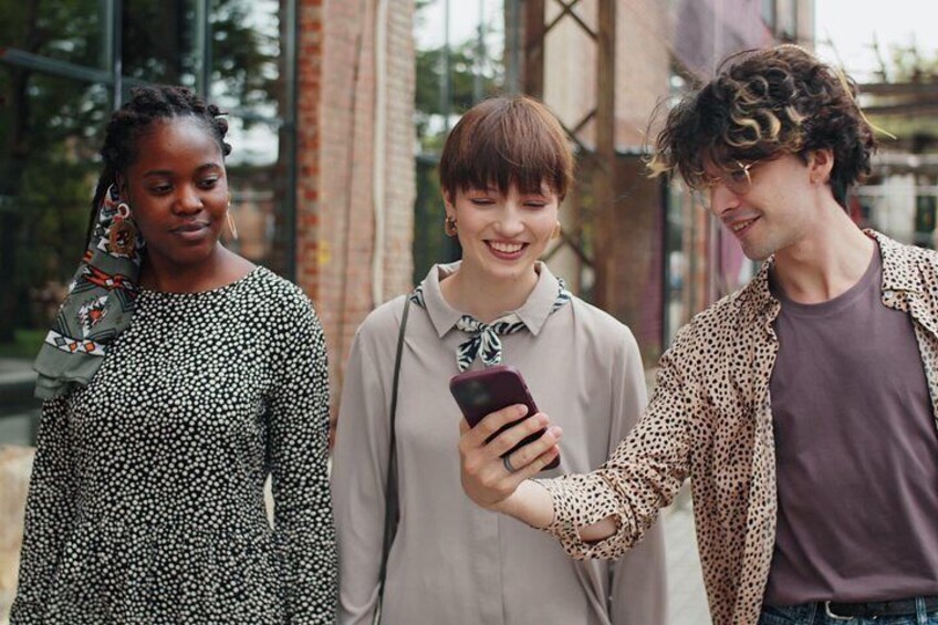 Tres personas están de pie al aire libre, una sosteniendo un teléfono inteligente. 4
