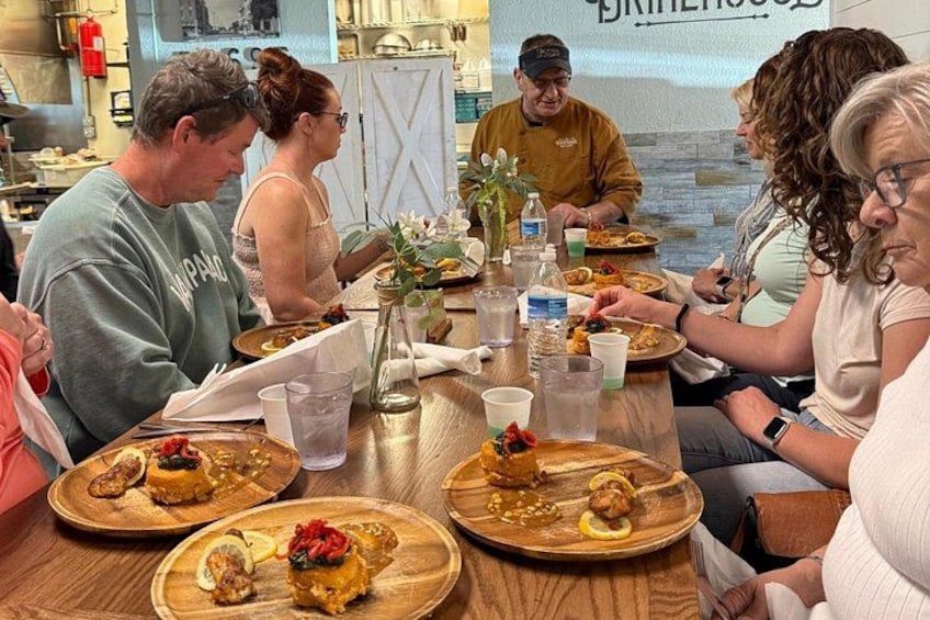 A group of people dining at a restaurant with wooden tables and plates of food. 4