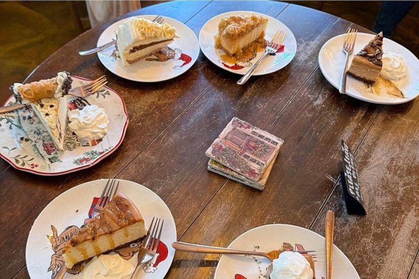 A wooden table with plates of various desserts, including pies and cakes, and a stack of magazines. 5