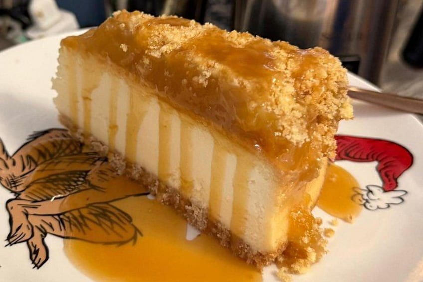 A slice of flan with caramel sauce on a plate with a bird illustration. 3