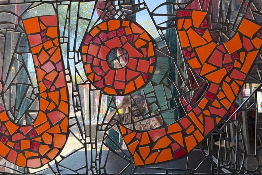 A stained glass window with the word 'LOVE' in orange and red mosaic tiles. 2