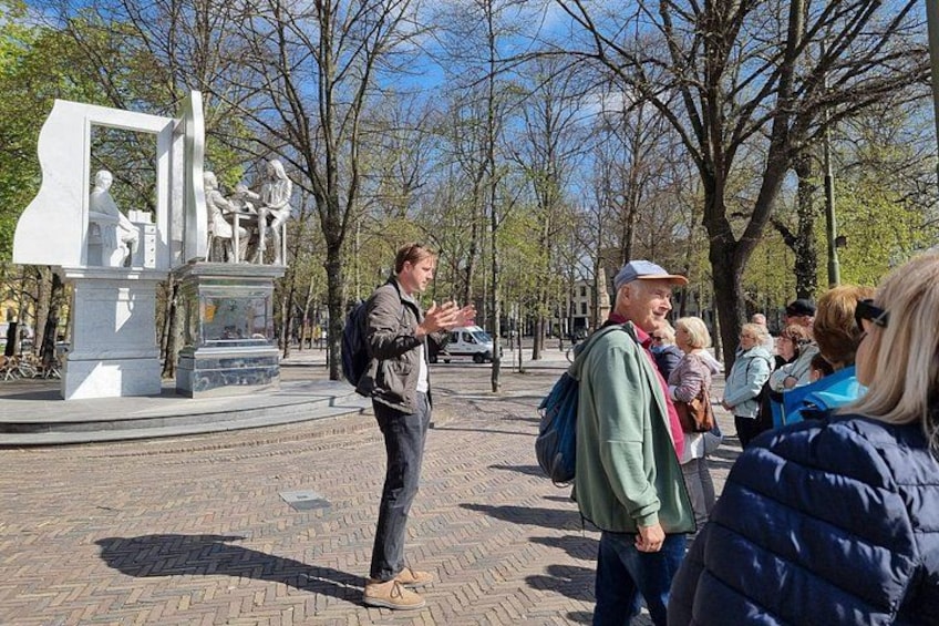 Un grupo de personas de pie en un parque, con una estatua al fondo. 1