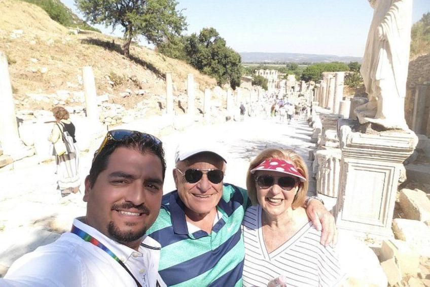 A group of people taking a selfie in an ancient ruin with columns and statues. 1