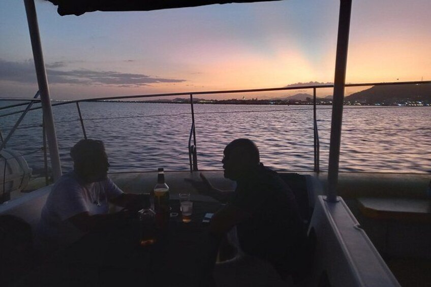 A boat with two people sitting at a table, a bottle, and glasses. 5