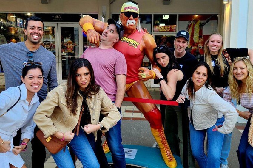 Un groupe de personnes posant à côté d’une statue de lutteur. 2