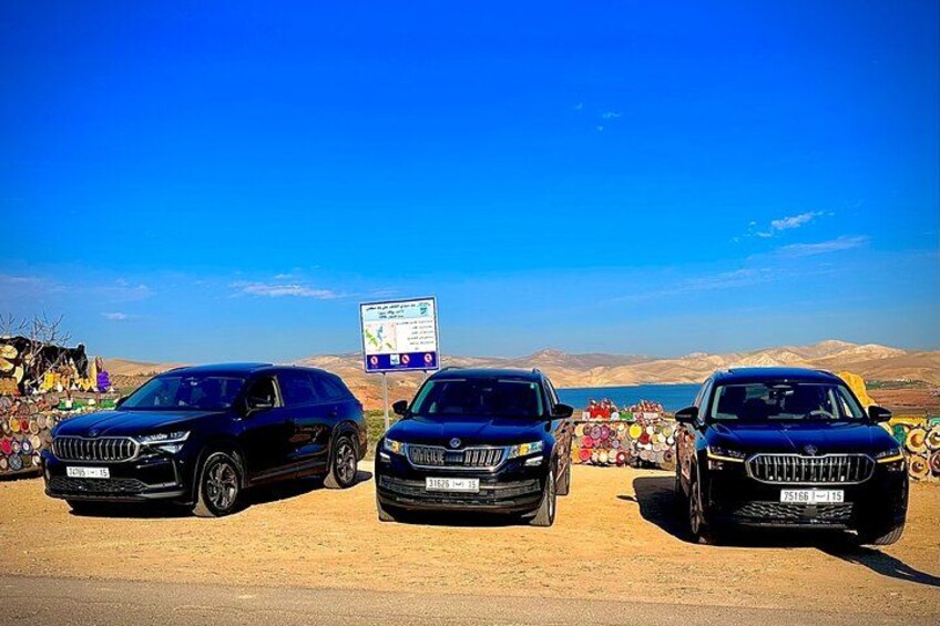 Trois SUV noirs étaient stationnés sur un chemin de terre, avec un ciel bleu dégagé et des montagnes en arrière-plan. 2