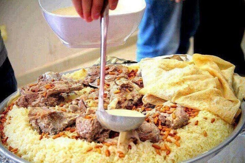 A large tray of rice with meat and nuts, a bowl, and a spoon. 2