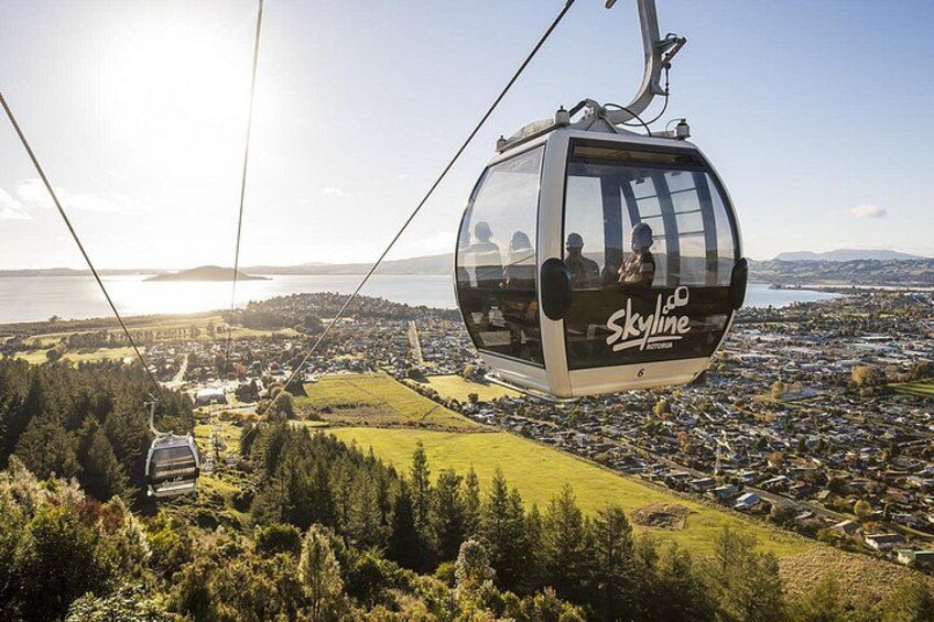 A cable car labeled 'Skyline' suspended over a town with a view of a lake and mountains in the background. 2