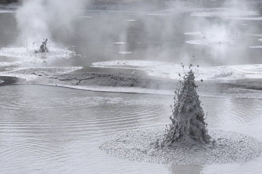 Un geyser dont la vapeur s'élève, entouré de dépôts minéraux. 3
