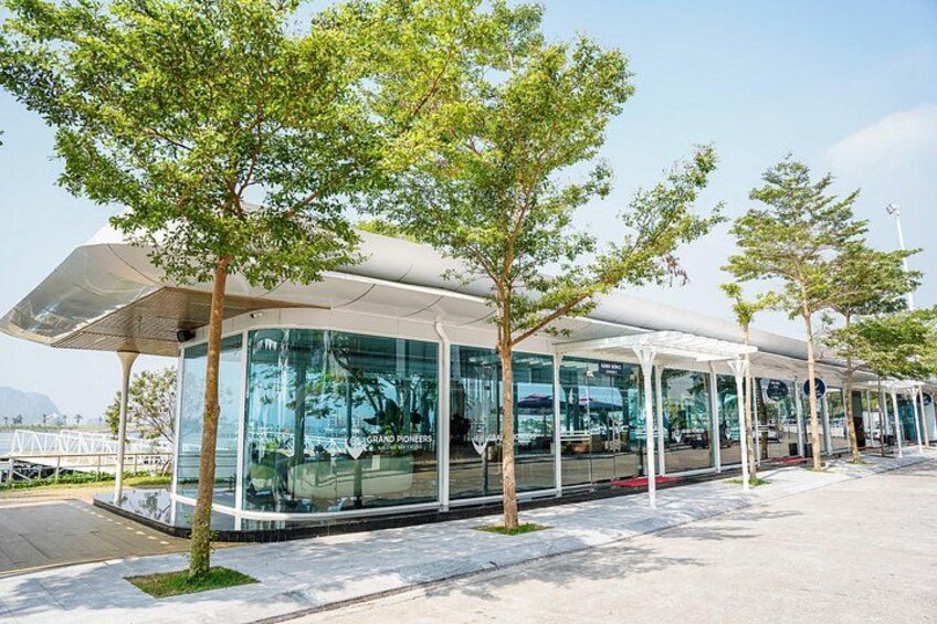 A modern bus station with glass walls and a covered waiting area. 3