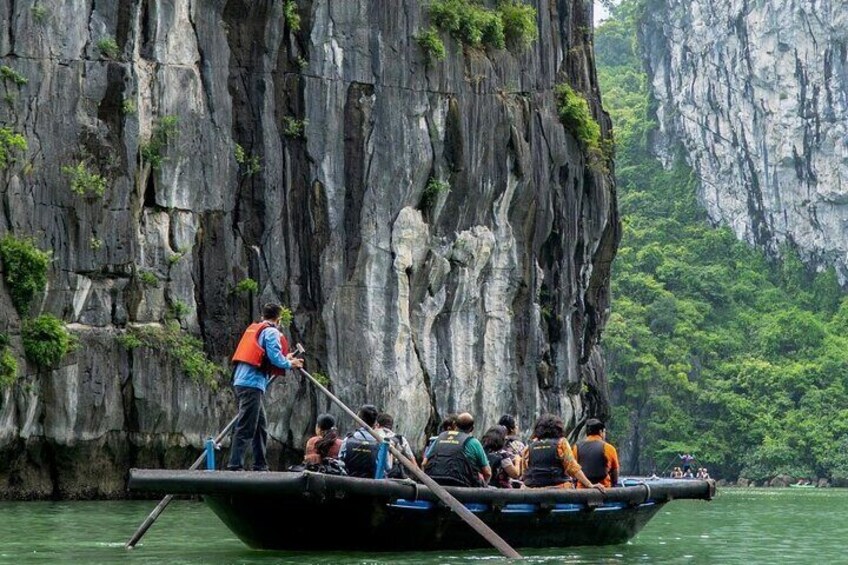 A boat with passengers rowing near a rocky cliff. 5