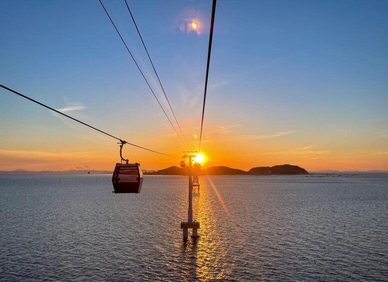 A cable car moving across a body of water during sunset. 5