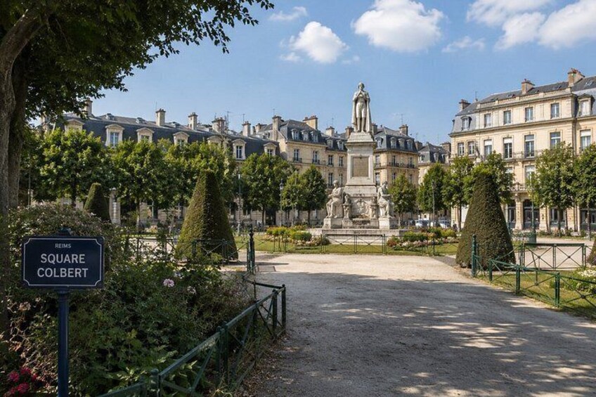 Una plaza histórica con una estatua, rodeada de arquitectura clásica y jardines bien cuidados. 2