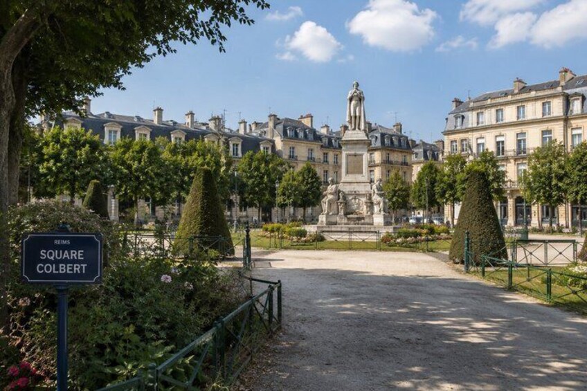 A historic square with a statue, surrounded by classical buildings and well-maintained gardens. 2