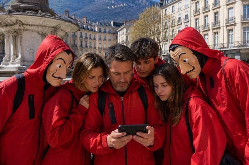 A group of people in red jackets gathered around a smartphone. 1