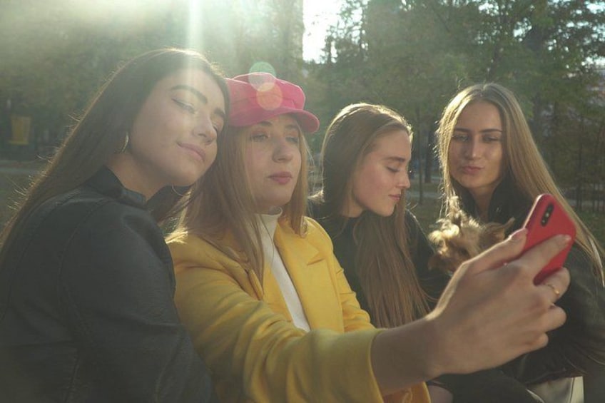 Four people outdoors, one holding a red smartphone. 4