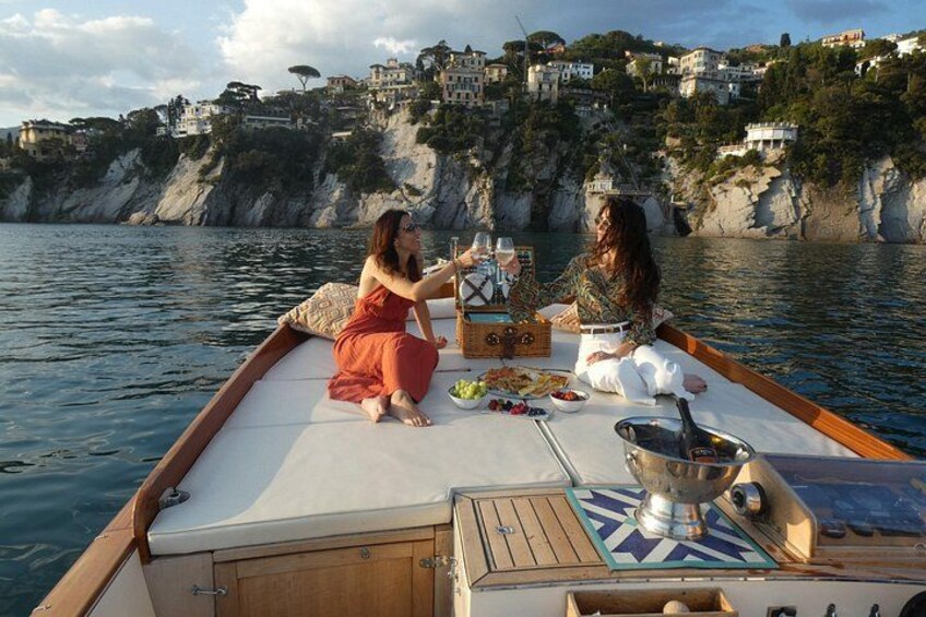 A boat with two people having a meal, surrounded by water and a coastal town in the background. 2