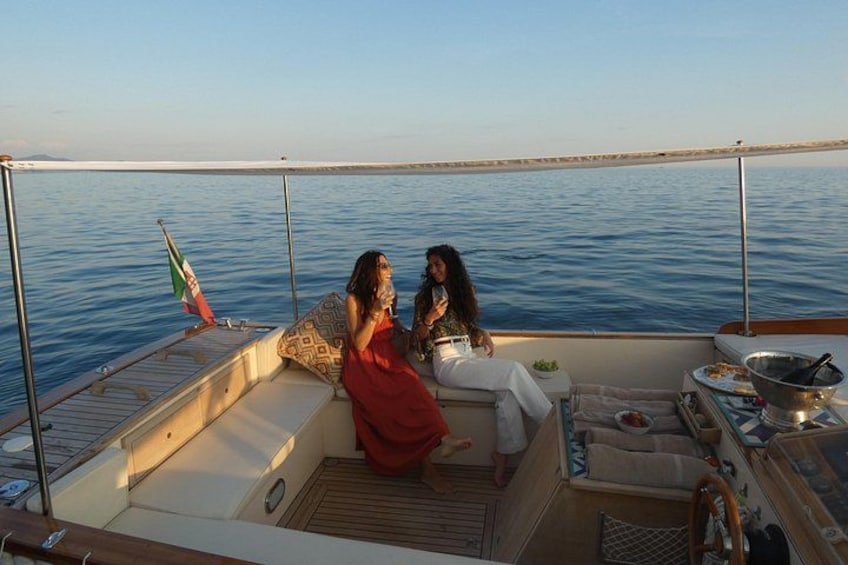 Two people on a boat, a flag, and a dining area with a table and chairs. 1