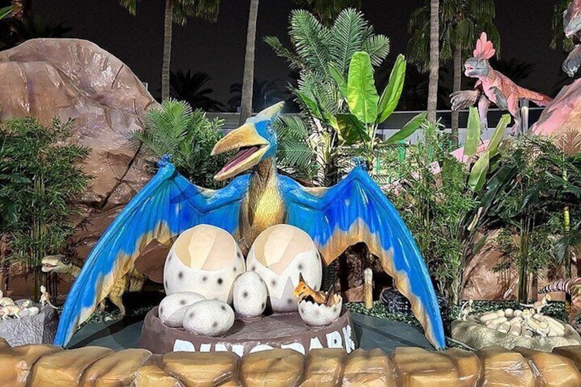 En utställning med dinosaurietema, med en stor, fågelliknande figur, ägg och en skylt med texten ”DINOSAURIE”. 2