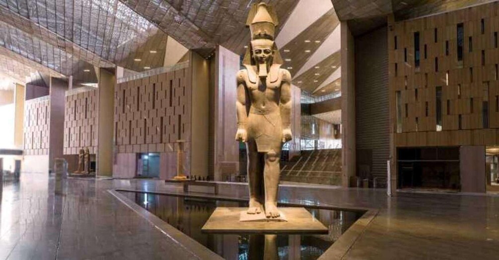 Une grande statue dans un espace intérieur moderne, doté d’un sol réfléchissant et de murs à motifs. 3