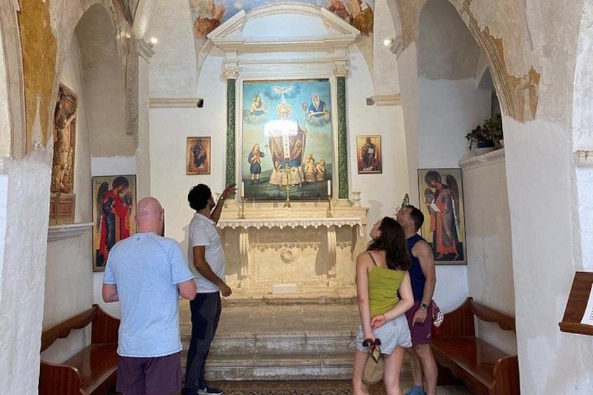 En grupp människor befinner sig inne i en kyrka och betraktar en religiös målning som hänger på altaret. 3