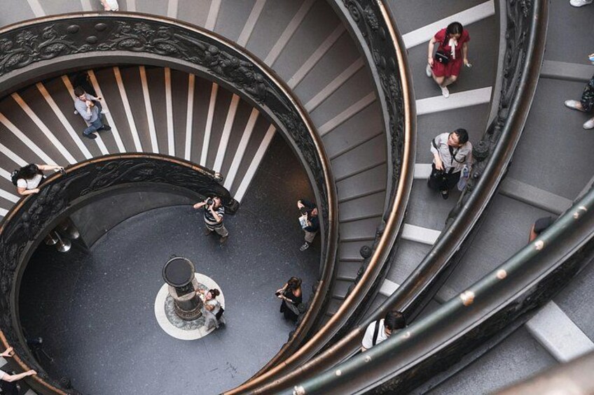 A spiral staircase with people walking up and down. 5