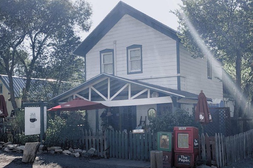 Une maison blanche avec un porche, un parasol rouge et une clôture en bois. 5