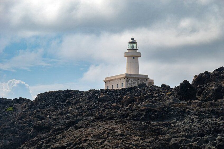 A lighthouse on a rocky cliff under a cloudy sky. 2