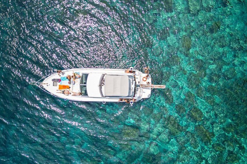 A boat anchored in clear turquoise waters with visible coral formations. 1