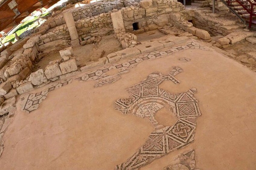 An ancient archaeological site with stone ruins and a circular mosaic pattern on the ground. 5