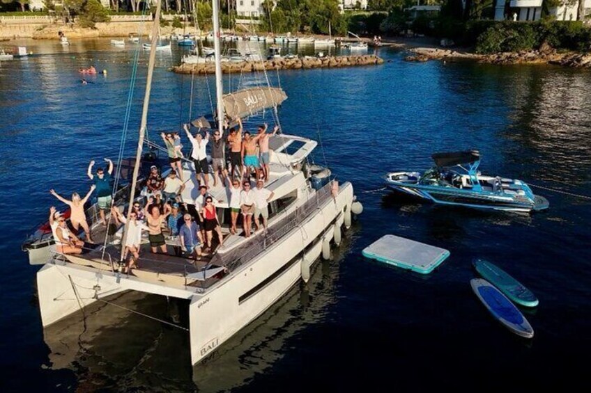 A group of people on a boat docked at a marina with smaller boats nearby. 1
