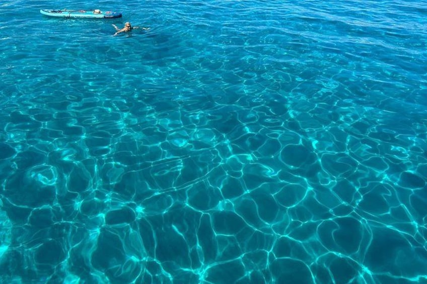 Acqua cristallina blu con un kayak e una persona che nuota. 2