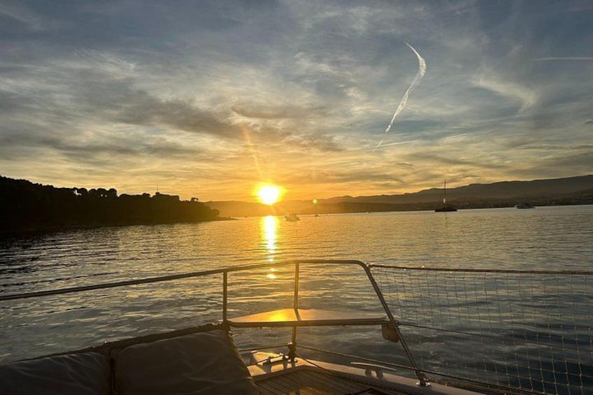 Tramonto su uno specchio d'acqua con una barca in primo piano e una costa lontana. 5