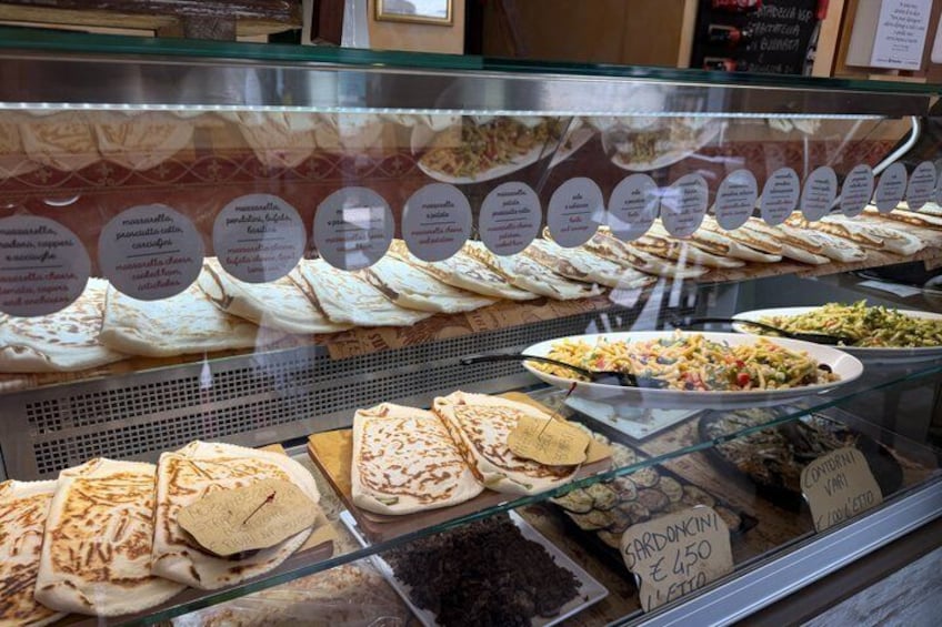 Eine Vitrine mit verschiedenen Sorten Fladenbrot und Gebäck, jeweils mit Namen und Preisen beschriftet. 2