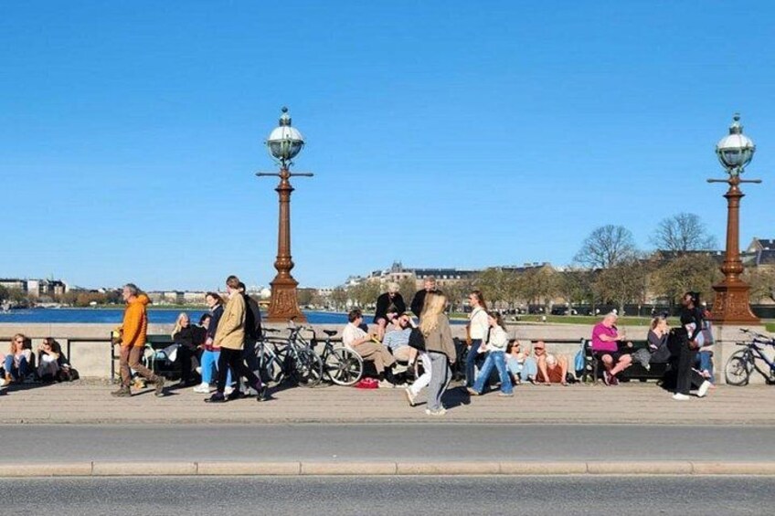 Un paseo fluvial con gente sentada y caminando, y bicicletas estacionadas a lo largo del camino. 5