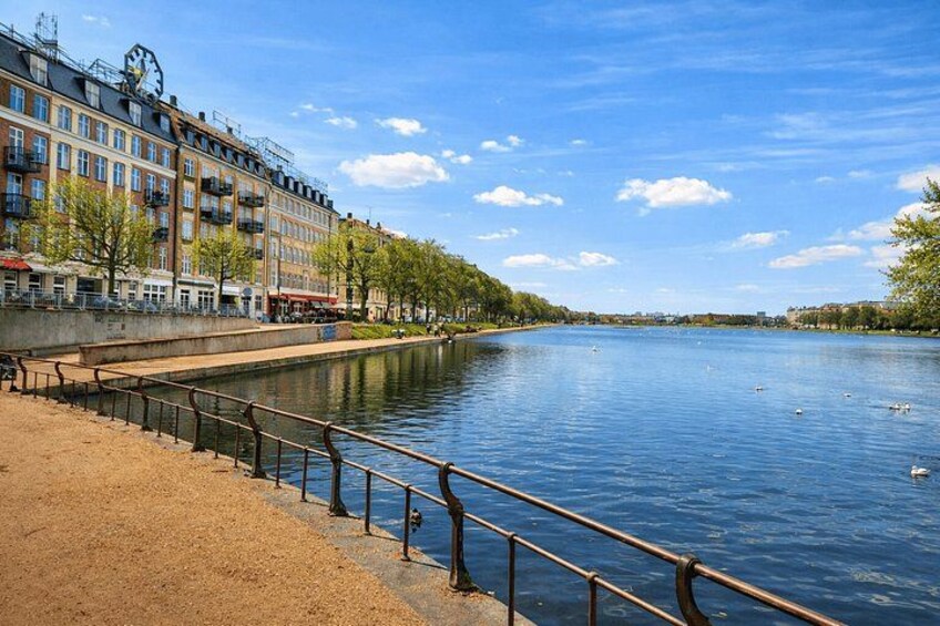 Un río con una pasarela de madera, edificios y árboles a lo largo de la orilla. 4
