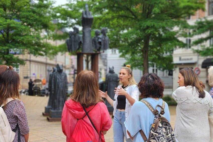 A group of people standing in a public square with a statue in the background. 4