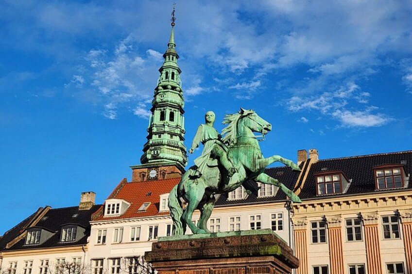 Eine Statue eines Mannes zu Pferd, ein Kirchturm und historische Gebäude. 3