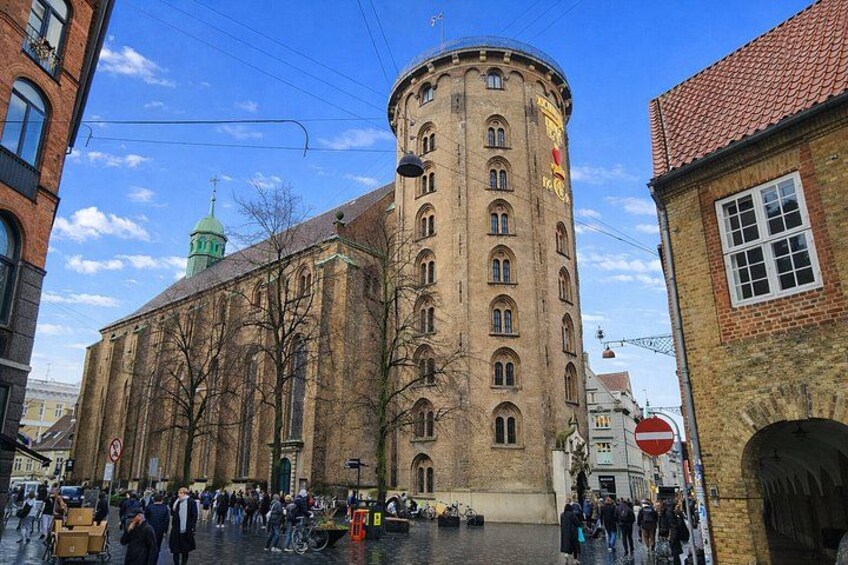 Ein historisches Gebäude mit einem Turm, einer grünen Kuppel und einer Menschenmenge. 2