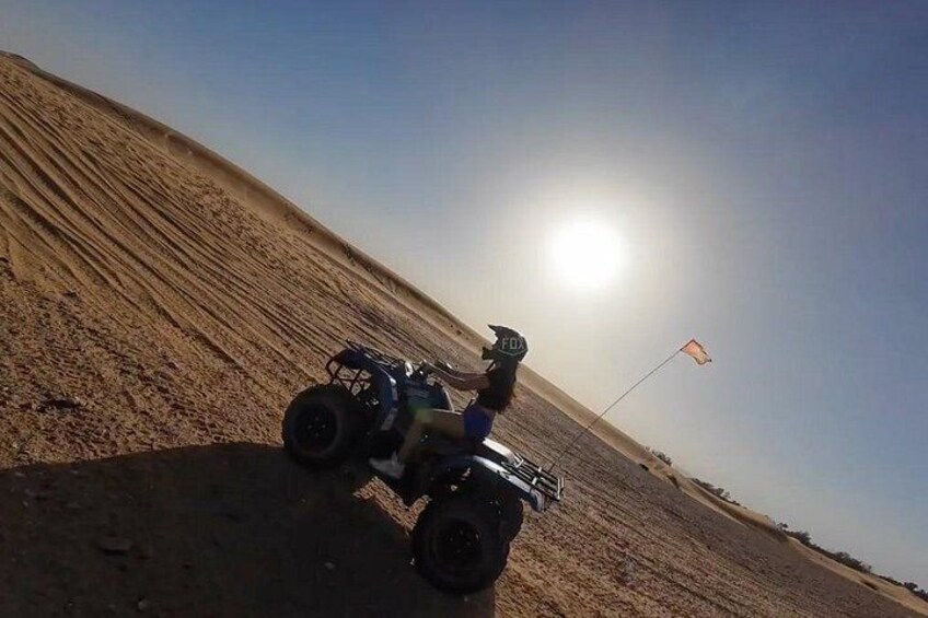 A quad bike on a sandy terrain with a flag in the background. 5