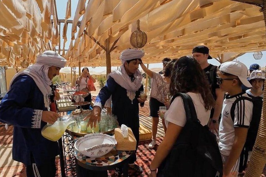 A group of people under a tented area with a food stall. 3