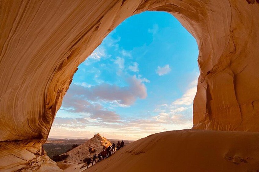 Un arco de roca con vistas a una montaña y un grupo de personas en la base. 2